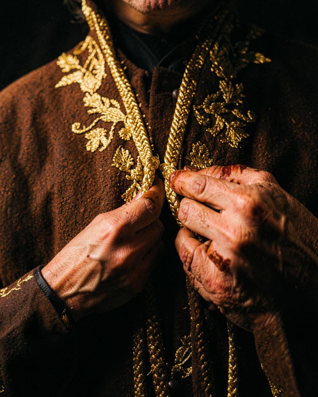 Hennaed hands holding layered 21K gold necklaces